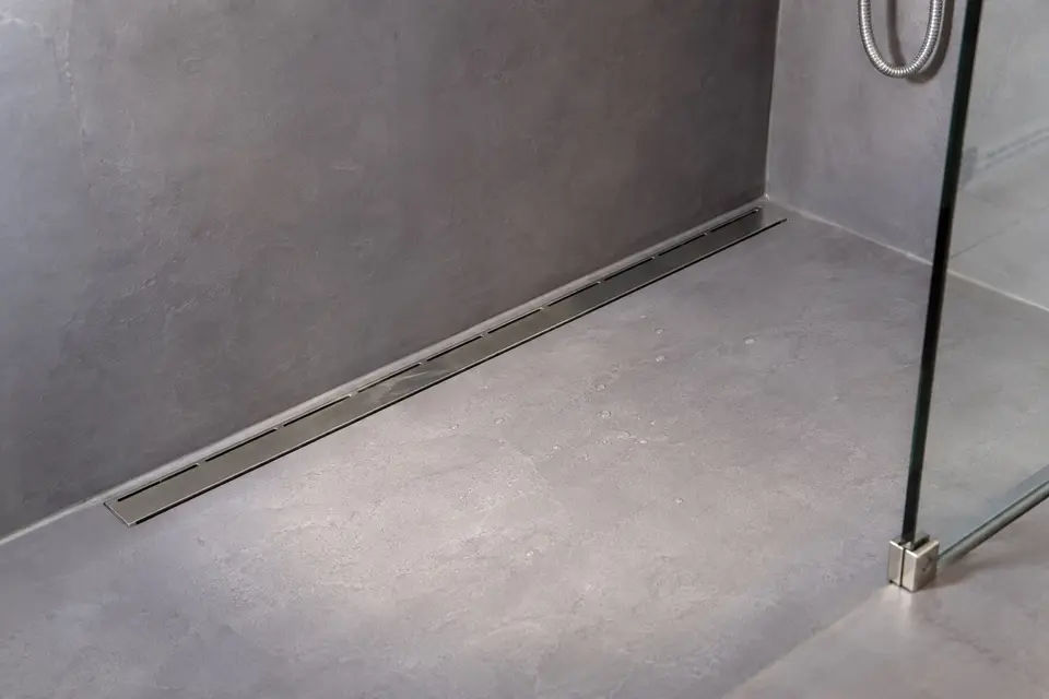 Lineární žlab u stěny v podlaze sprchy ze stěrky