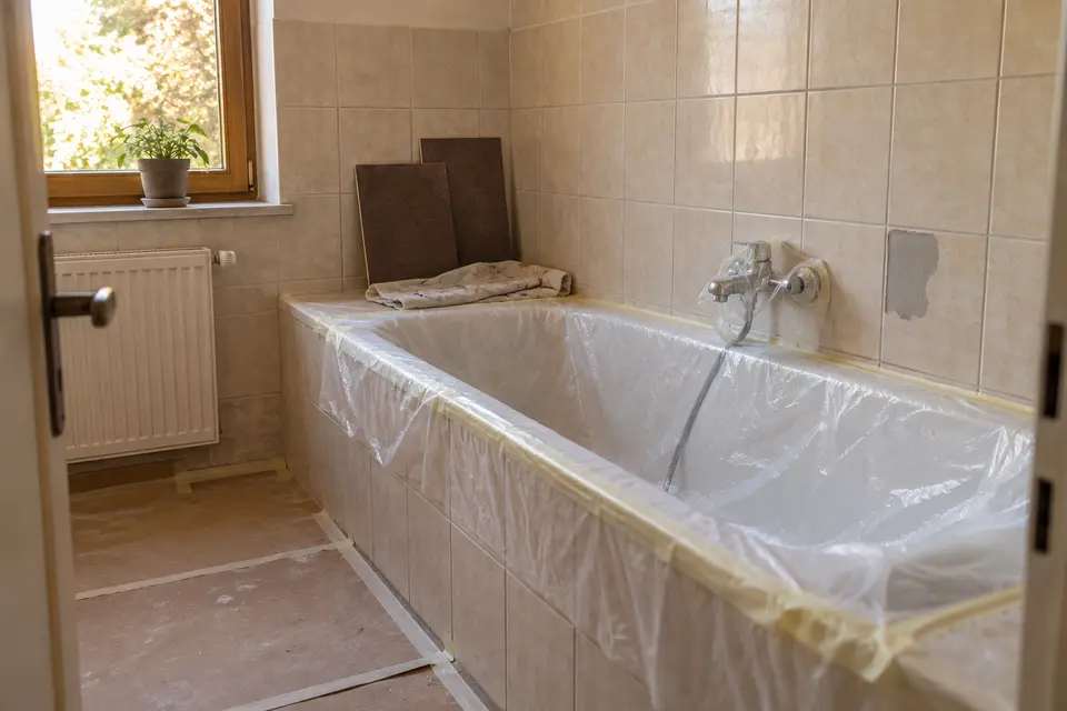 Původní vana zakrytá fólií, při renovaci koupelny zůstává na místě