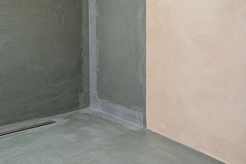 Hydroizolace v koutu sprchy před nanesením stěrky, vedle hotová mandlová stěrka